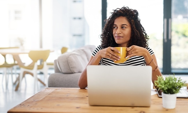 Ragazza beve tazza di caffè davanti al pc