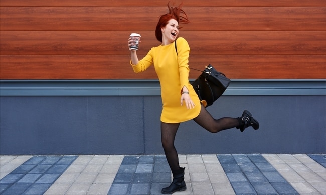 Ragazza con vestito giallo che corre felice con una tazza di caffè